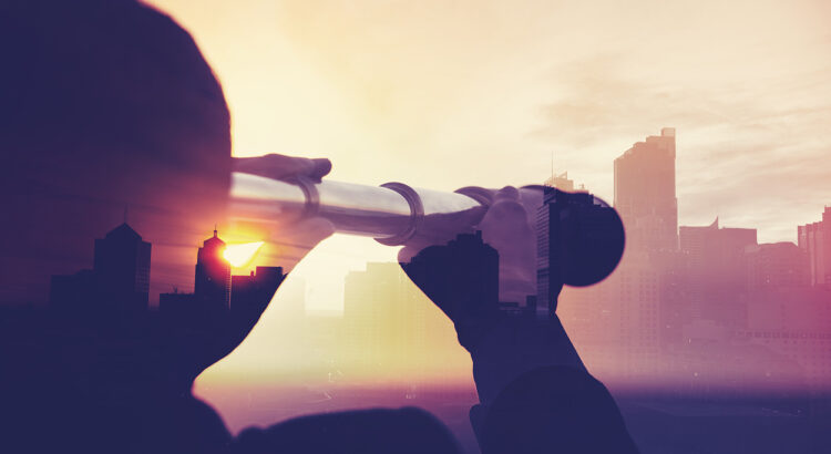 Business man in suit with cityscape montage. The man is unrecognizable and you cannot see his face. He is superimposed onto a city skyline at sunset. He is holding a telescope looking into the city. Success, vision concept with copy space.