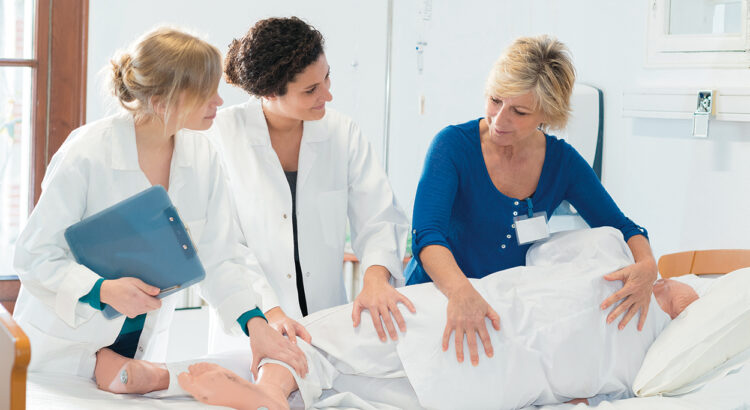 nurses practicing how to roll a patient with dummy