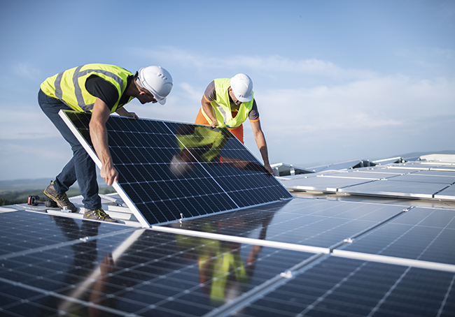 Team of two engineers installing solar panels on roof