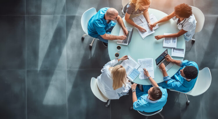 Medical team engaged in a discussion around a round table, viewed from a high angle.
